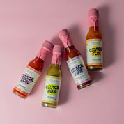 Four Crack Fox hot sauce bottles with pink wax seals on a pink background. Flavours: Churrache, Bintang, Davidson Plum, and Hot Jamaica. Organic and spicy free.