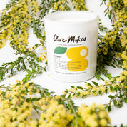 An image of a Candle made by Clare Makes candles, with the text: Henry the wattle, Australian Botanical Collection with a background of yellow flowers and text: Soy Wax Candle Handmade in Sydney