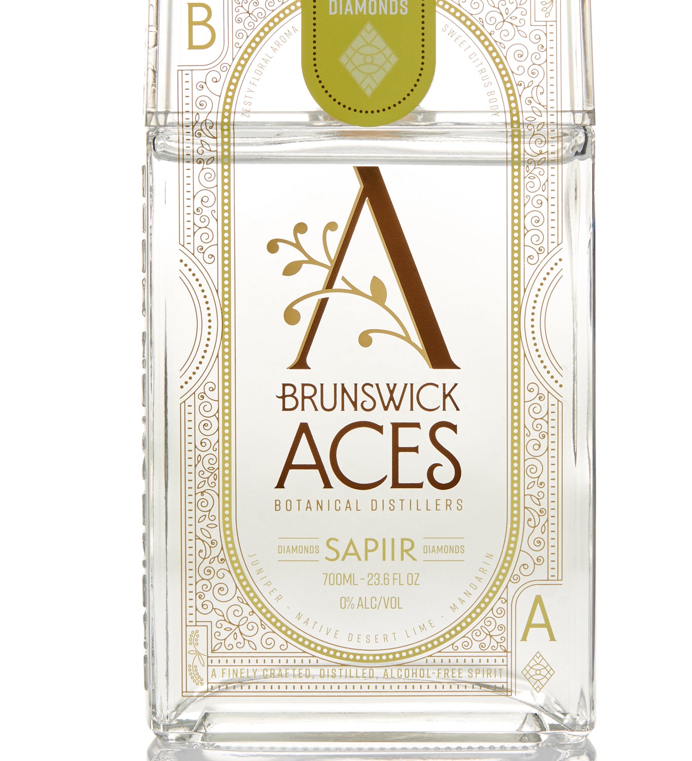 A clear bottle of Brunswick Aces Sapiir, an alcohol-free distilled botanical spirit. The label features an ornate "A" logo and highlights the use of native Australian desert lime and mango.