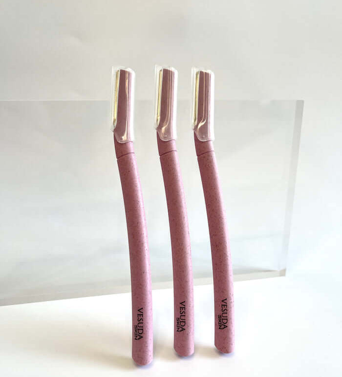 Three pink razors with "VESUDA SKIN" printed on curved handles, standing upright on a white surface. Ergonomic design highlighted.