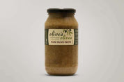 A glass jar of "Olive's Olives" Pure Olive Paste from the Macedon Ranges. The jar is filled with a dark green paste and has a black lid. The label features a hand-drawn illustration of olives and the words "Pure Olive Paste" in a handwritten style.