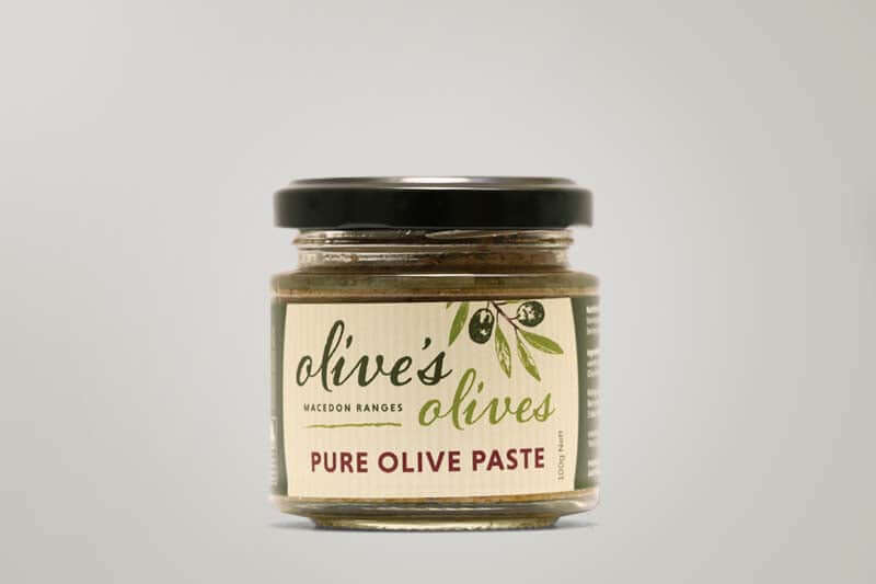 A glass jar of "Olive's Olives" Pure Olive Paste from the Macedon Ranges. The jar is filled with a dark green paste and has a black lid. The label features a hand-drawn illustration of olives and the words "Pure Olive Paste" in a handwritten style.