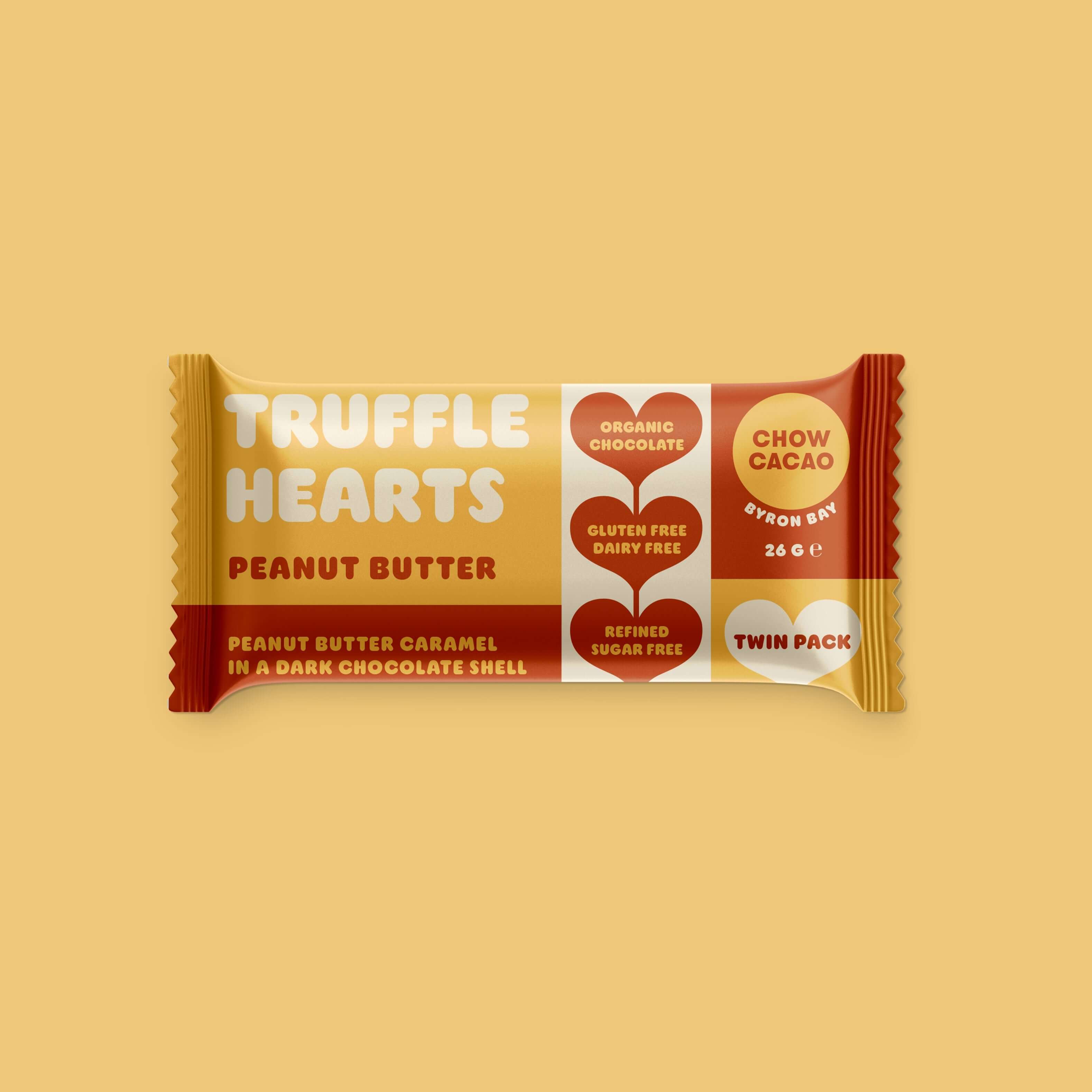 A photo of a yellow package of "Truffle Hearts" chocolate. The package is sealed and has a label with the brand name "Chow Cacao," and information about the product, such as "Peanut Butter Caramel," "Gluten Free," and "Dairy Free."