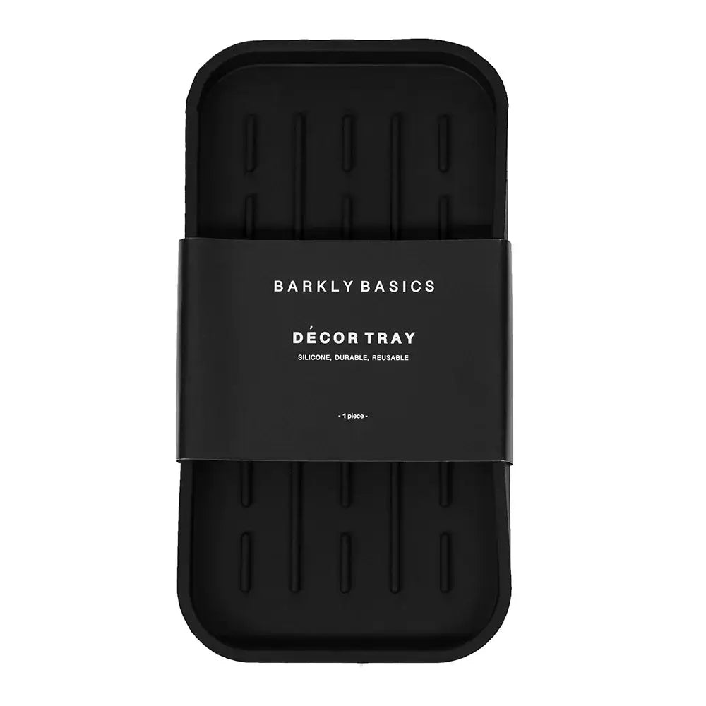 A black silicone decor tray with raised lines on the surface. The tray is packaged with a white label that reads "Barkly Basics Décor Tray" and states it is silicone, durable, and reusable.