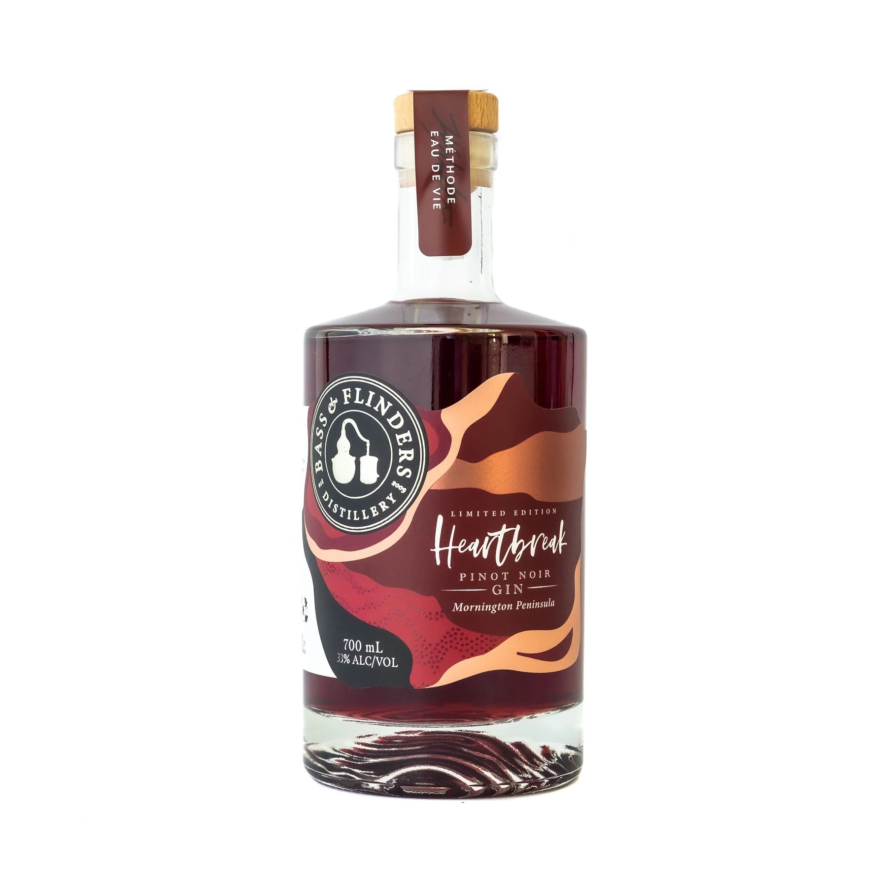 A bottle of Bass & Flinders Heartbreak Pinot Noir Gin. The bottle is clear and shows the deep red-colored gin inside. The label reads "Heartbreak Pinot Noir Gin" and "Limited Edition." The bottle is 700ml and has an alcohol content of 30%. It is made on t